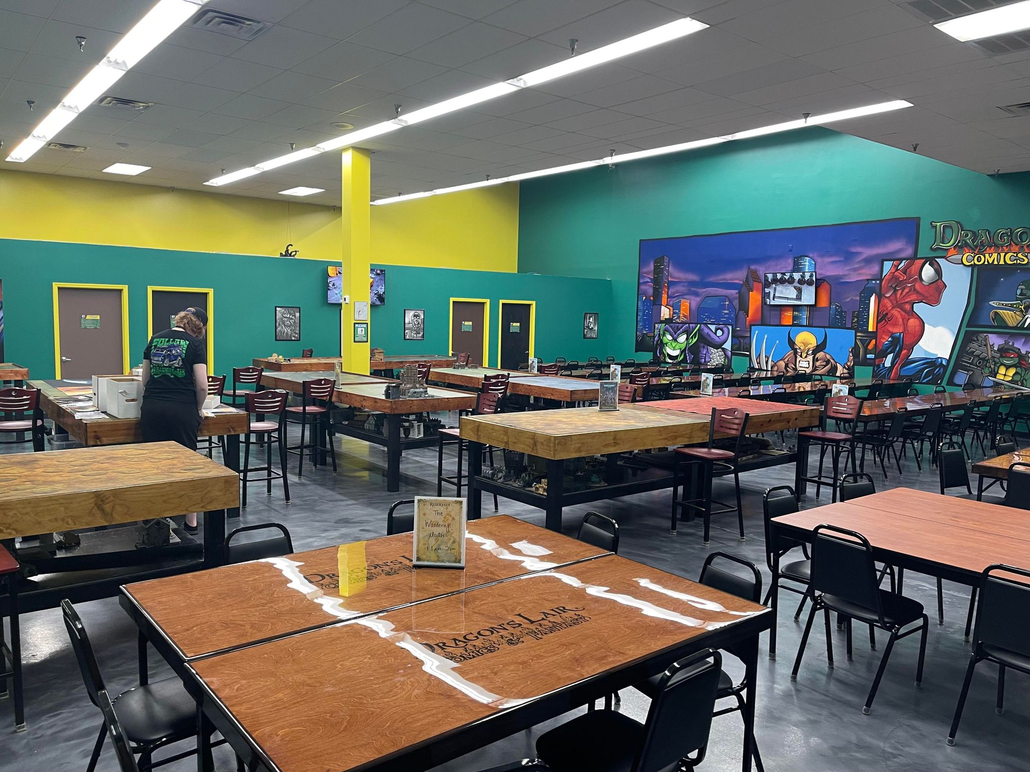 photo of wooden tables with Dragon's Lair logo printed on the surface in a brightly painted room