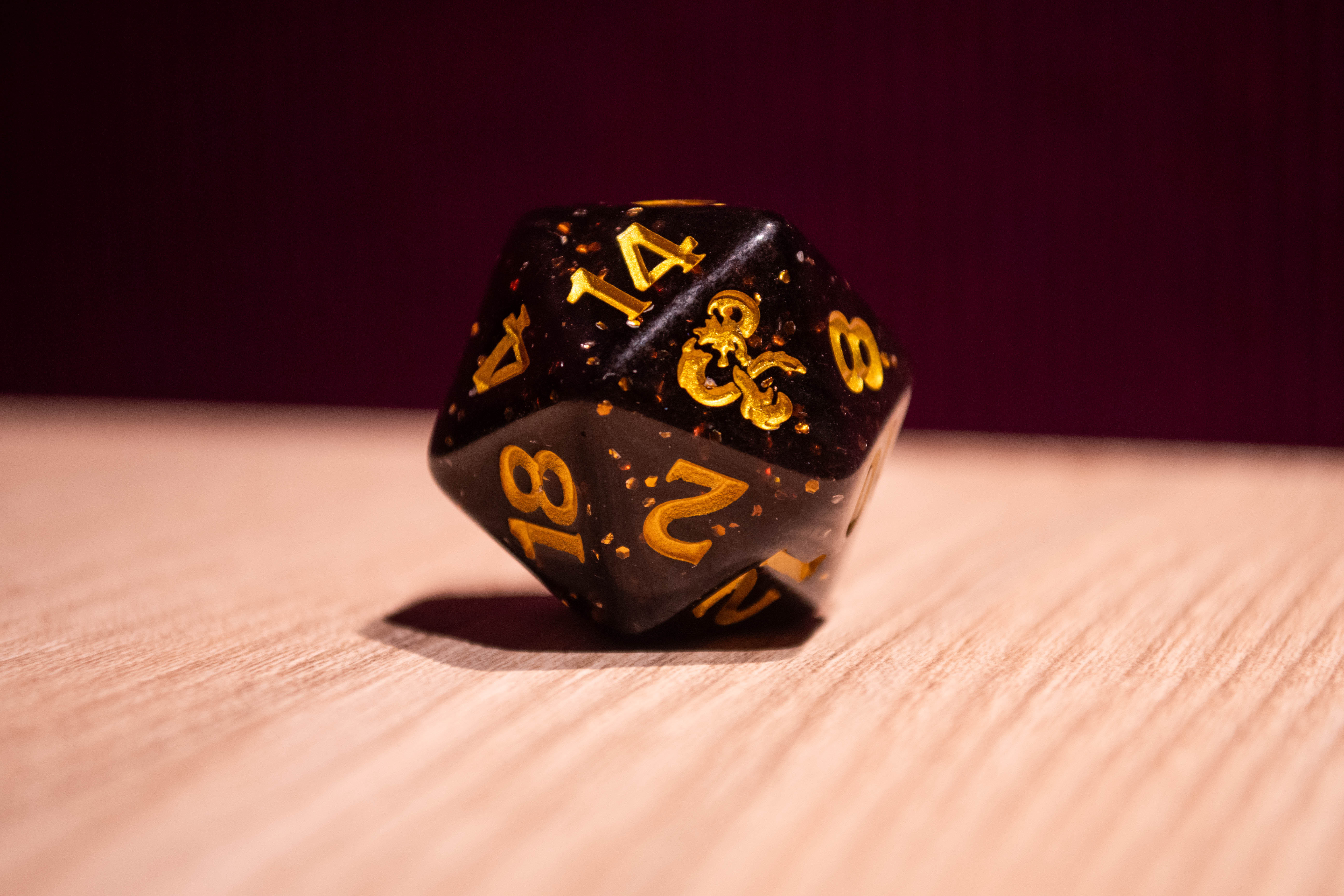 Photo of a black d20 with gold flecks and numbering.